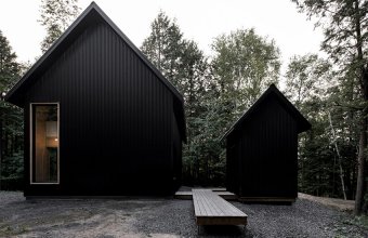 O casă neagră din metal se ascunde într-o pădure din Quebec